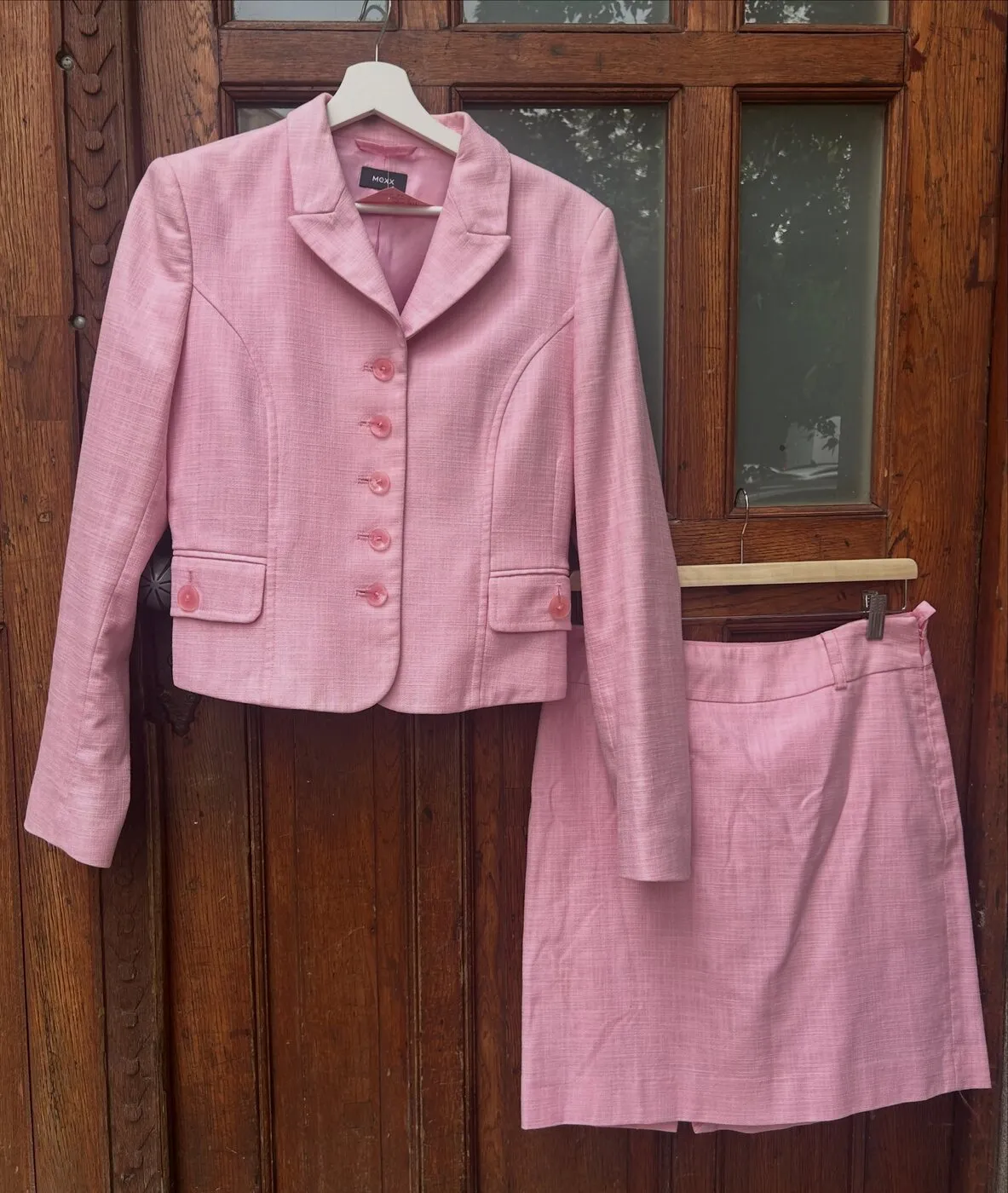 Rózsaszín tweed blézer és hozzá tartozó miniszoknya, a bolt fa bejárati ajtaján.